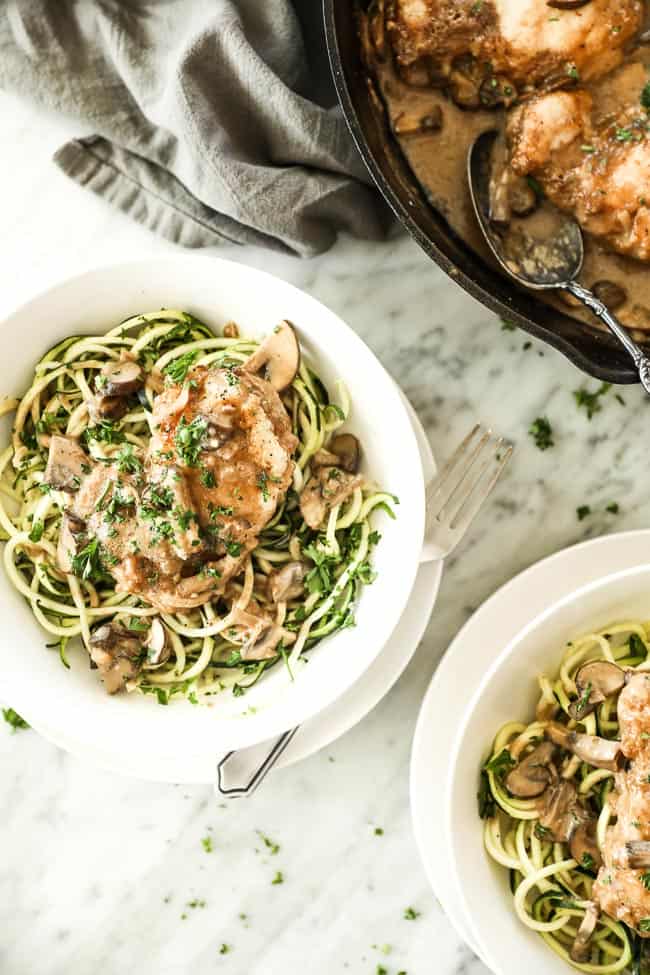Easy chicken marsala with chicken, mushrooms and a creamy sauce served in a bowl over zucchini noodles with a fork on the side. Fresh chopped parsley sprinkled on top. 