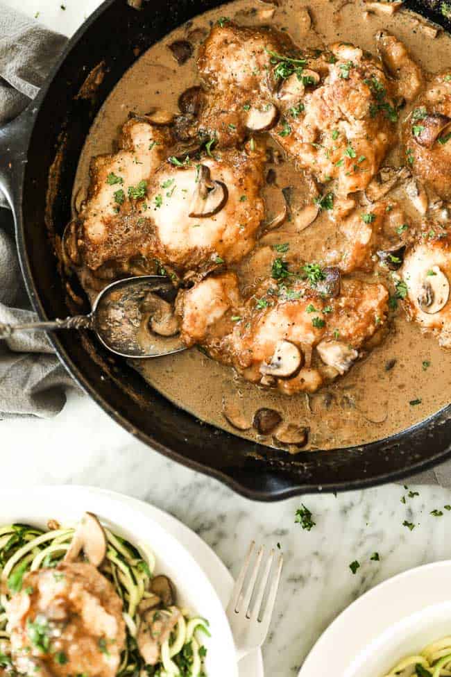 Easy chicken marsala with chicken, mushrooms and a creamy sauce in a cast iron skillet. Fresh chopped parsley sprinkled on top. 