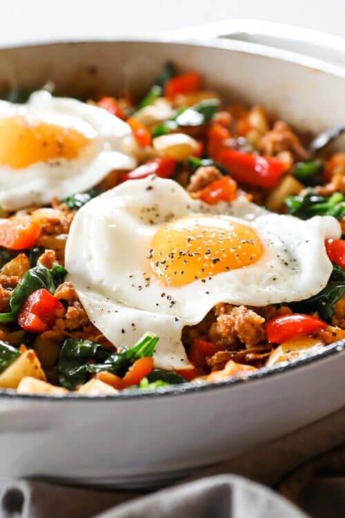 Angled vertical image of easy chorizo hash in skillet with fried eggs on top.