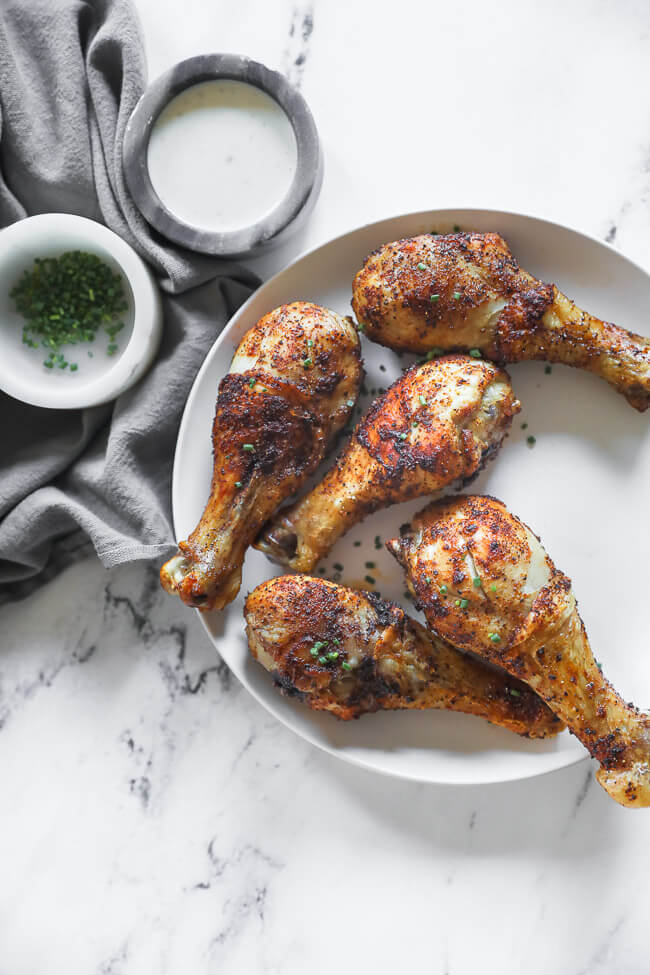 Air fryer chicken drumsticks on a plate with chives sprinkled on top