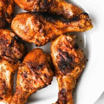 overhead image of grilled chicken drumsticks on a plate with grill marks