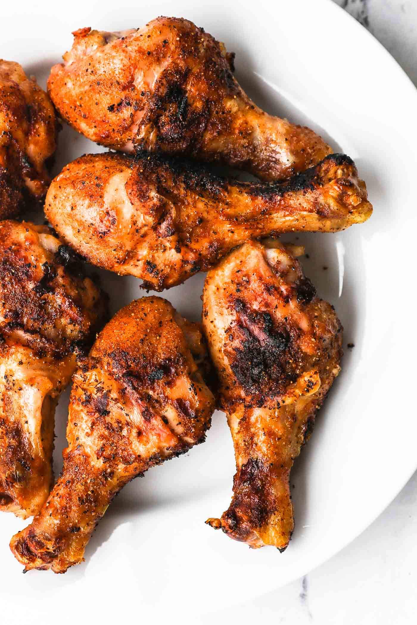 overhead image of grilled chicken drumsticks on a plate with grill marks