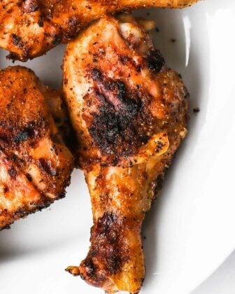 Close up overhead shot of 3 grilled chicken legs on a plate