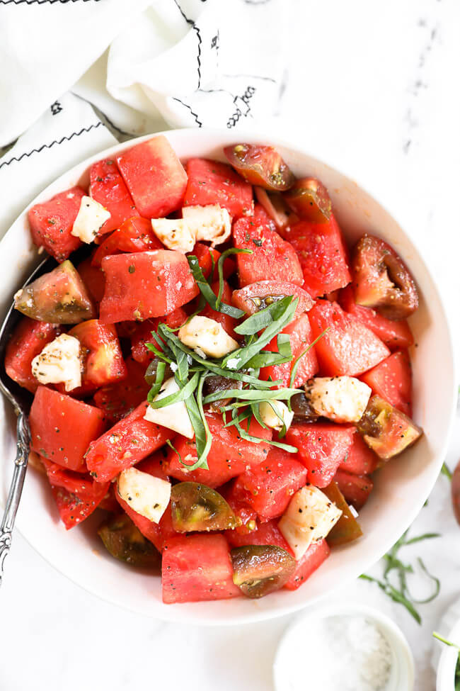 Close up image of tomato watermelon salad in a bowl with fresh chopped basil on top.