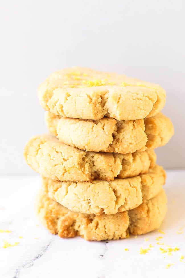 Stack of five gluten free shortbread cookies with lemon zest sprinkled on top.