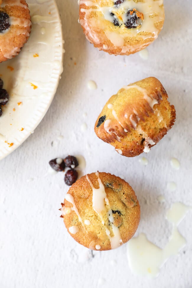 Overhead image of muffins on a plate with a few scattered off to the side. Orange icing drizzled everywhere. 