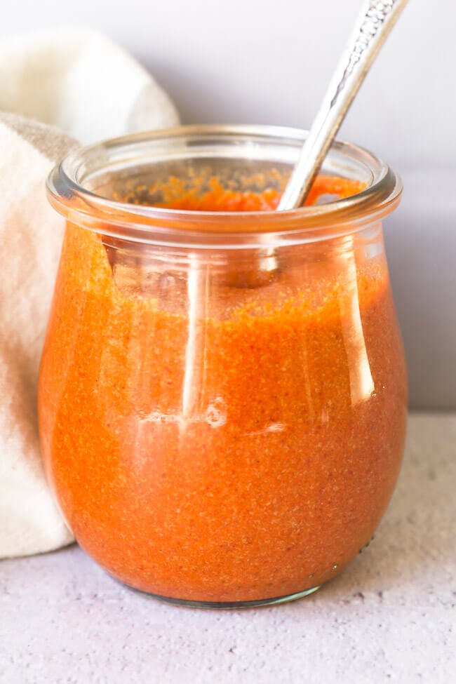 Homemade keto buffalo sauce in a small jar with spoon coming out