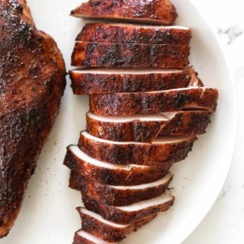 Overhead image of smoked chicken breast cut into strips on a plate.