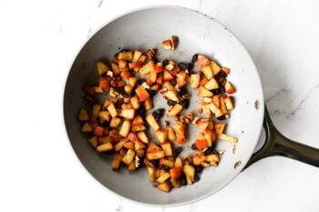 Apples, cinnamon, raisins and chopped pecans heated up in a skillet to serve as a pancake topping.