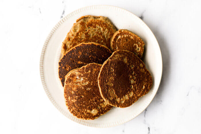 A plate full of oat flour pancakes once finished cooking.
