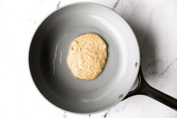 Oat flour pancake batter added to a hot skillet.