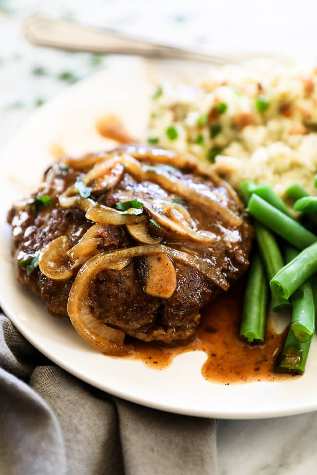 Salisbury steak on plate with green beans and mashed potatoes close up angle shot
