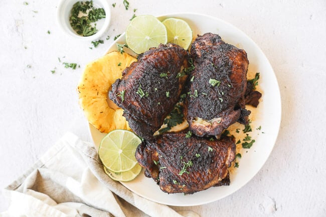 Easy slow cooker jerk chicken on a plate with pineapple and lime horizontal image