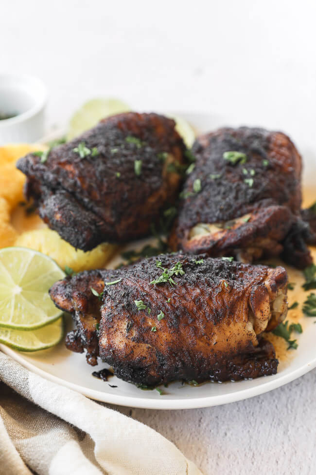 Easy slow cooker jerk chicken on a plate with pineapple and lime vertical angle image