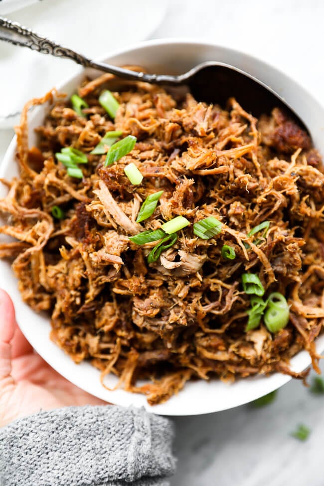 bowl of shredded slow cooker pulled pork with chopped green onions on top