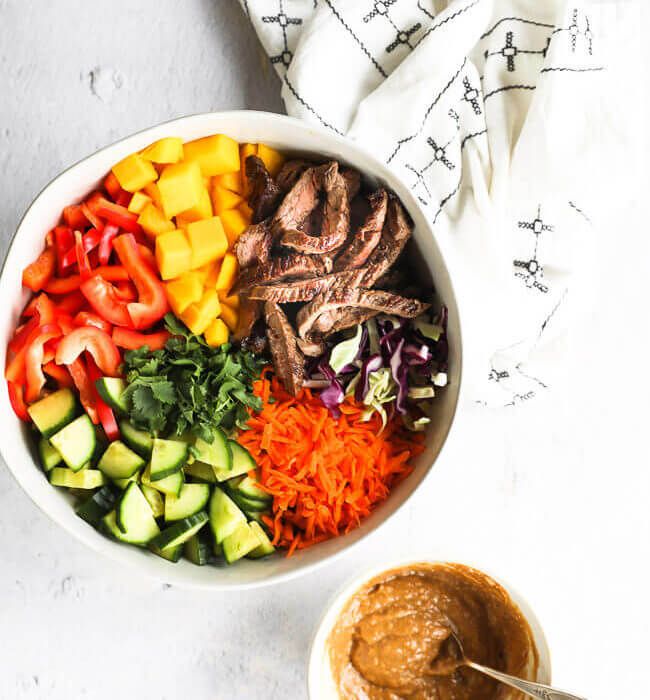 Easy thai beef salad with chopped veggies in bowl and sauce on the side