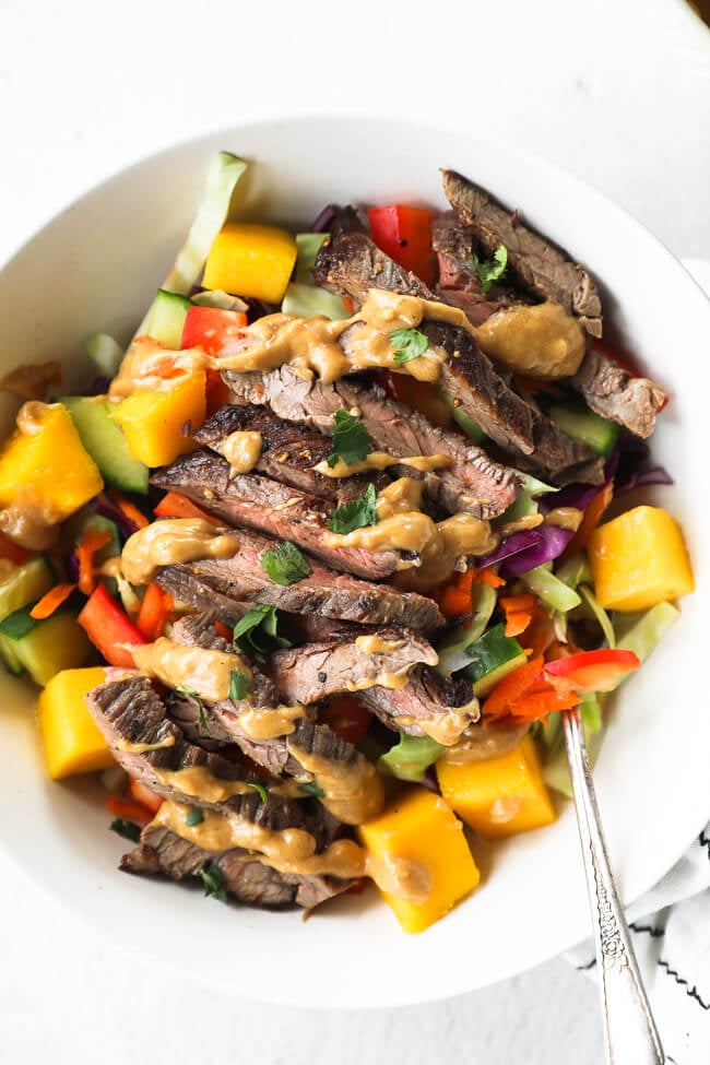 thai beef salad served in a bowl with cashew sauce drizzled on top.