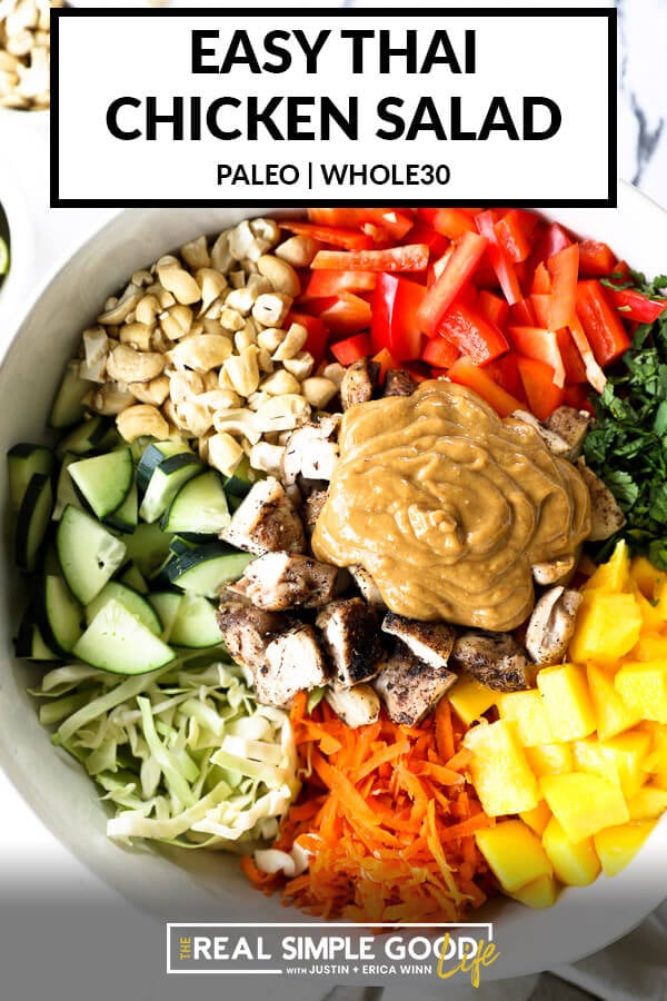 Vertical overhead image of thai chicken salad in a large serving bowl with all the ingredients separated out - cabbage, cucumber, cashews, red bell pepper, cilantro, mango, carrots, chicken and a "peanut" sauce. Text overlay at top. 