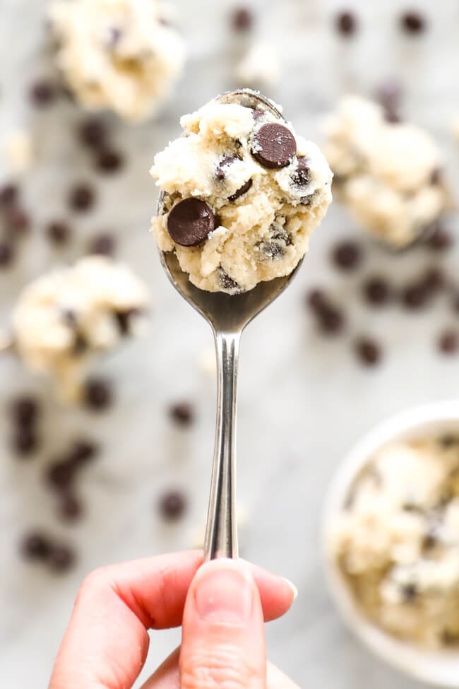 Vertical image of holding a spoonful of edible cookie dough 