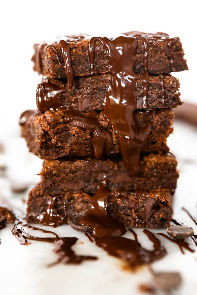 Vertical image of stack of egg-free brownies with chocolate sauce cascading down the side of the stack. 
