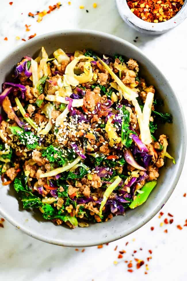 Egg roll in a bowl with sesame seeds on top. Made with cruciferous veggies, ground pork and a savory sauce.