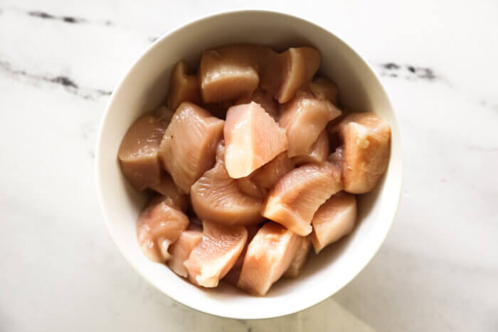 Raw cut up chicken breast pieces in a bowl