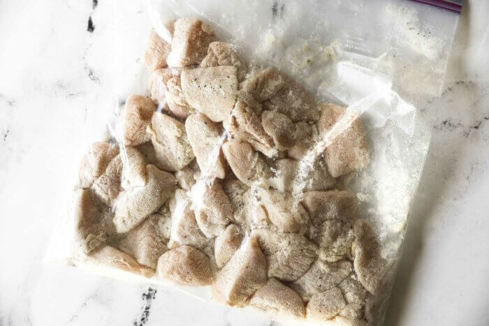 Chicken pieces coated with flour in a zip top bag