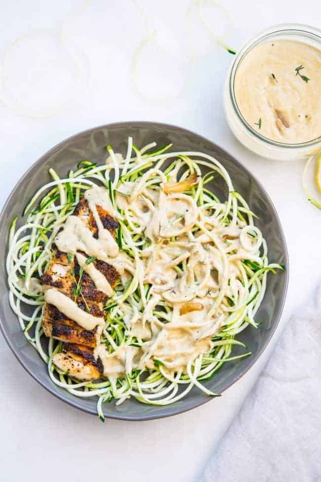 Creamy garlic chicken on a plate with zoodles and creamy sauce on top