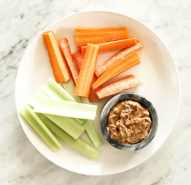 Sliced carrots and celery on a plate with almond butter