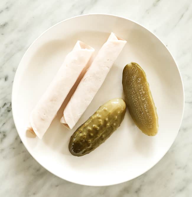 Pickles and rolled lunch meat on a plate