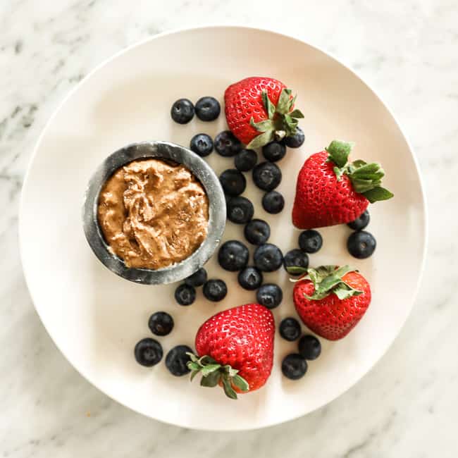 Strawberries and blueberries on a plate with almond butter