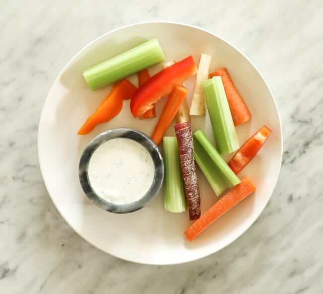 Sliced carrots, celery and bell pepper on a plate with ranch dressing