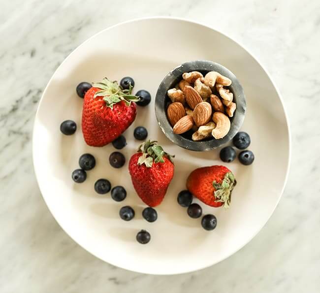 Strawberries and blueberries on a plate with mixed nuts