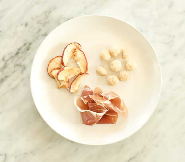 Dried apples, macadamia nuts and prosciutto on a plate