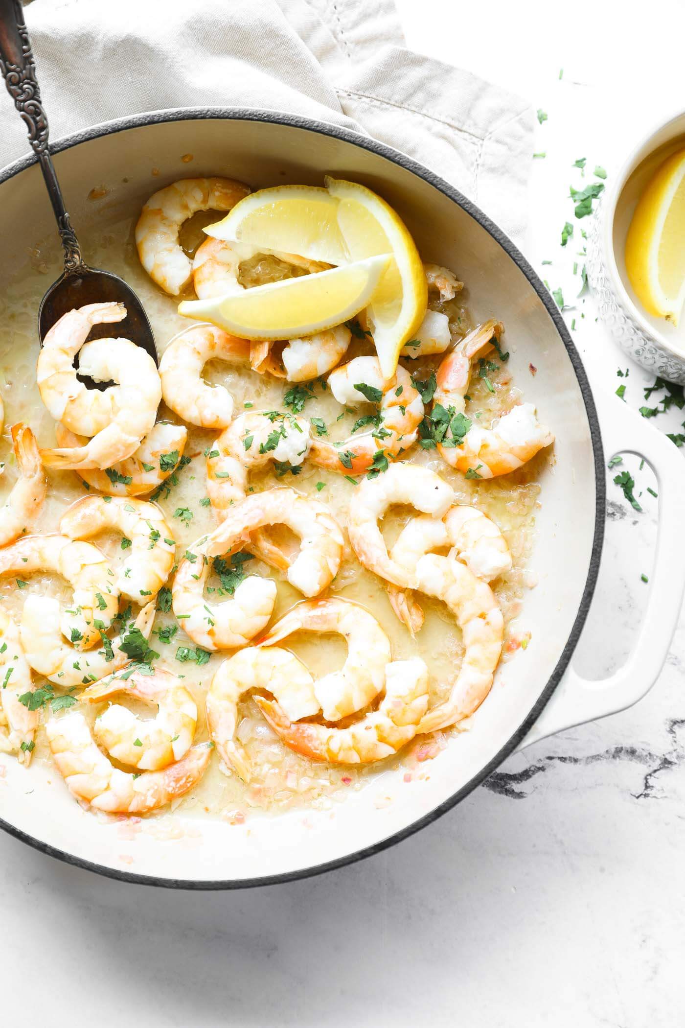 Overhead close up of skillet full of garlic butter shrimp sprinkled with chopped cilantro.