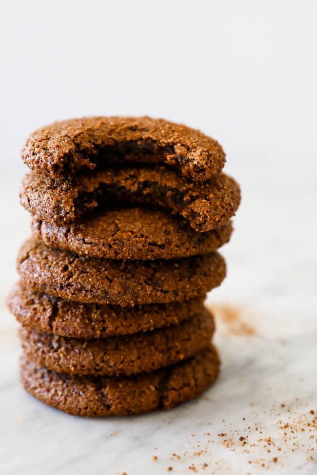 Straight on vertical image of stack of ginger molasses cookies with top two cookies having a bite taken out. 