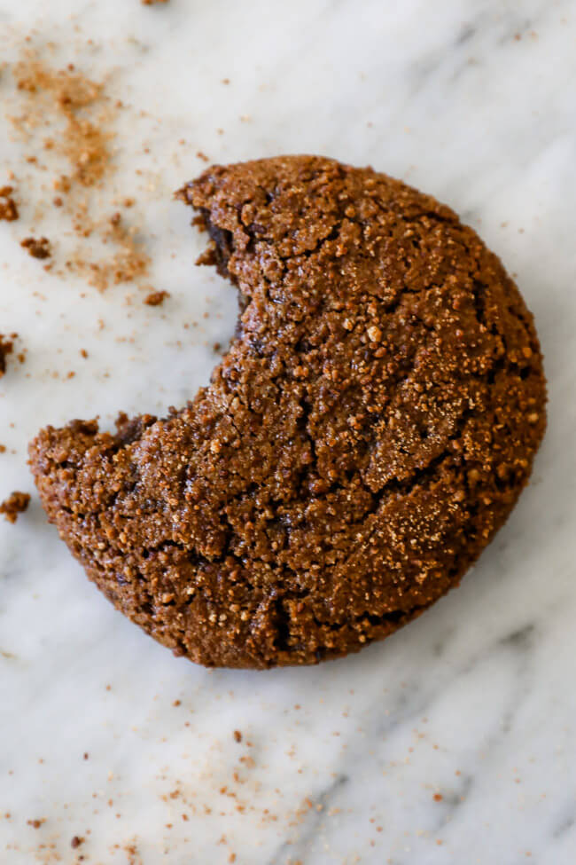 Overhead vertical image of one ginger molasses cookie with a bite taken out of it. 