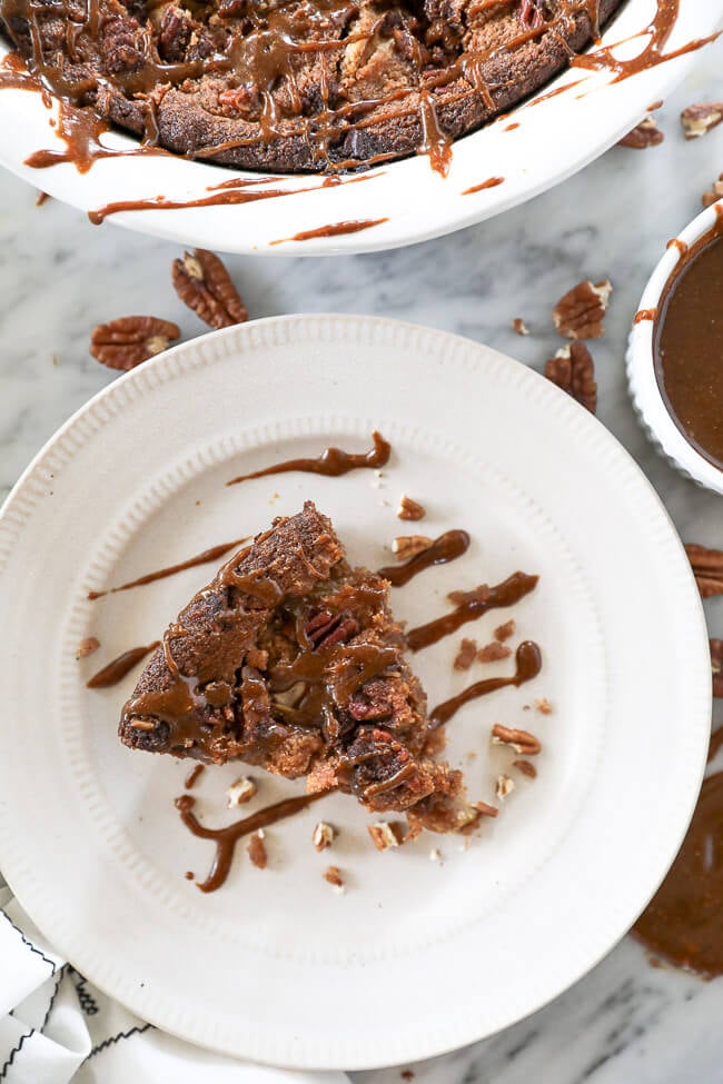 Piece of gluten-free apple cake served on a plate with caramel sauce drizzled on top. 