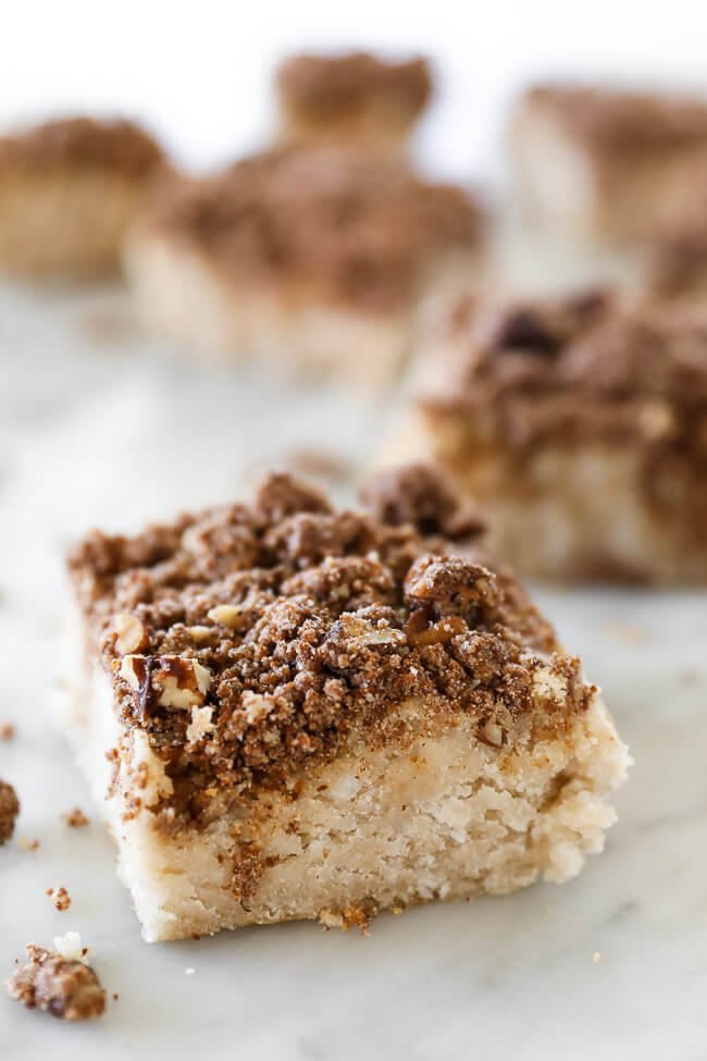 Close up of an angled image of one square of gluten free coffee cake with more squares blurry in the background. 