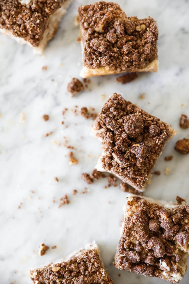 Gluten free coffee cake squares spread out in a vertical snaking line with crumbs all over. 