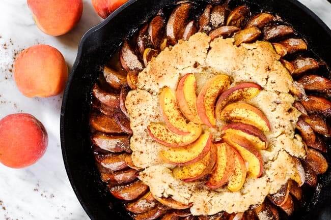 Gluten free peach cobbler in cast iron skillet with peaches and cinnamon.
