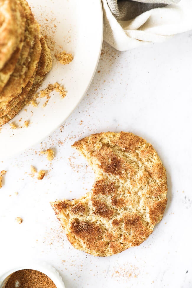 Overhead vertical image of one snickerdoodle cookie with a bit taken out of it. 