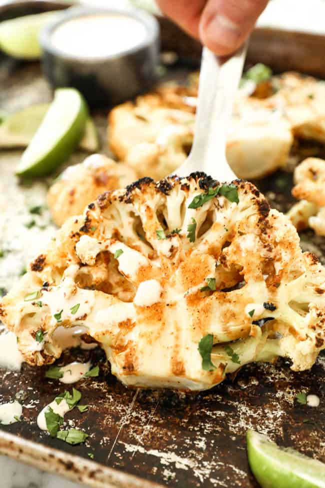 Lifting cauliflower steak off cooking sheet with a spatula. 