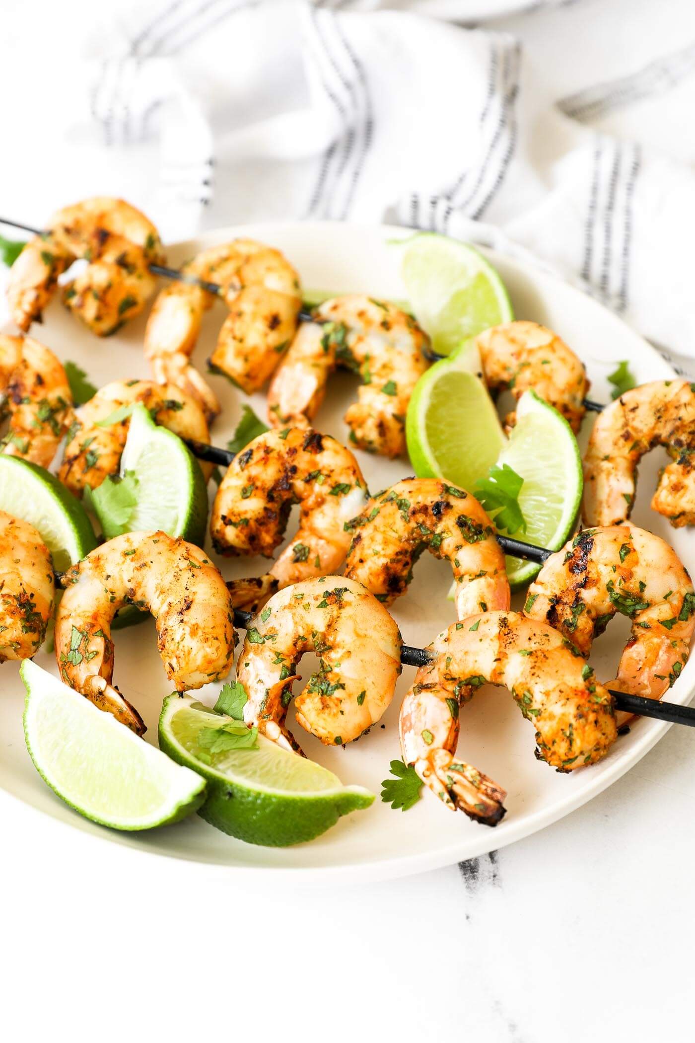 Angled image of skewers on a plate. Grilled shrimp kabobs with