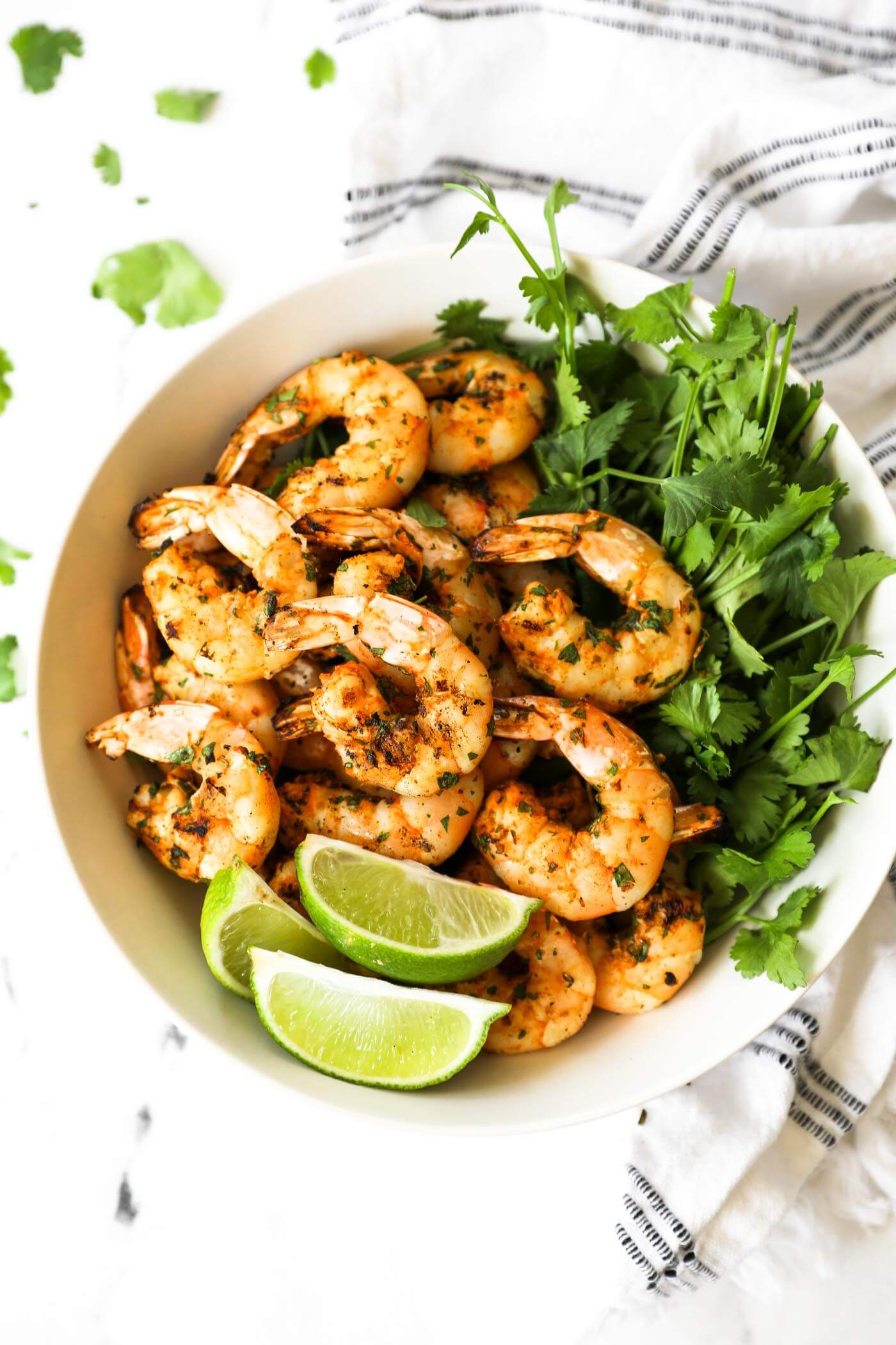 Shrimp pulled off the kabobs and piled in a bowl with fresh cilantro and lime wedges.