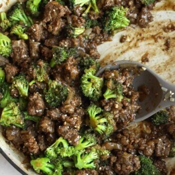 Ground beef, broccoli florets, and savory sauce come together in this easy one pan broccoli stir fry, all mixed in a large skillet with a serving spoon resting inside.