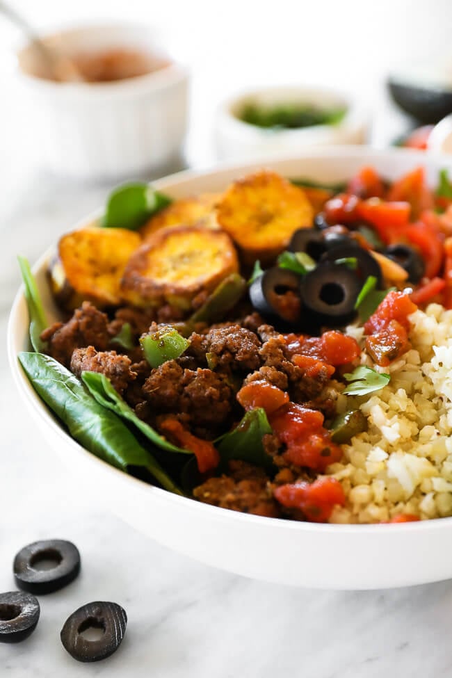 ground beef taco bowl with greens, plantains and cauli rice close up angle image