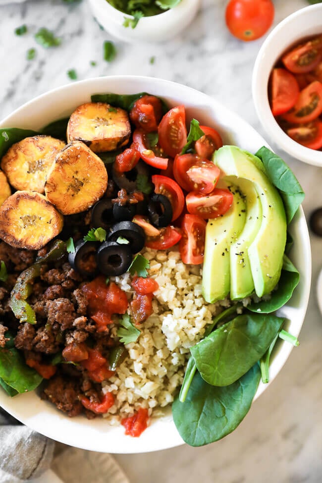 ground beef taco bowl with greens, plantains and cauli rice close up vertical image