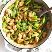 Black pepper chicken stir fry with celery and green bell pepper in a pan with sauce and a spoon scooping in