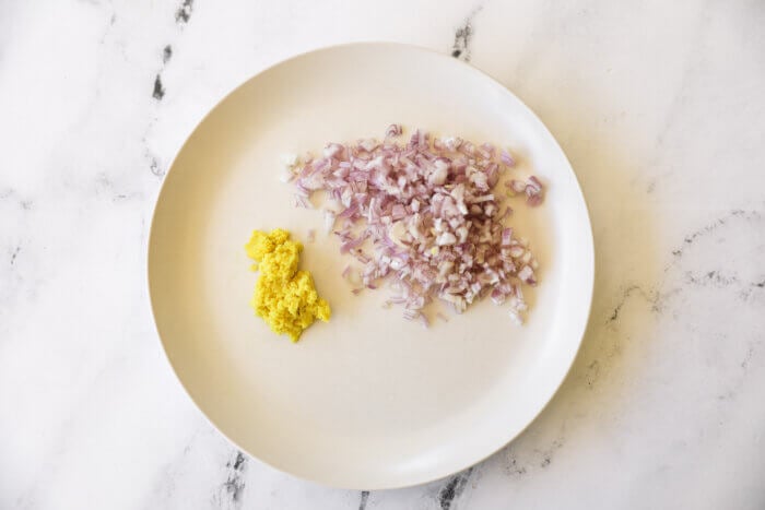 Chopped shallot and grated ginger on a white plate